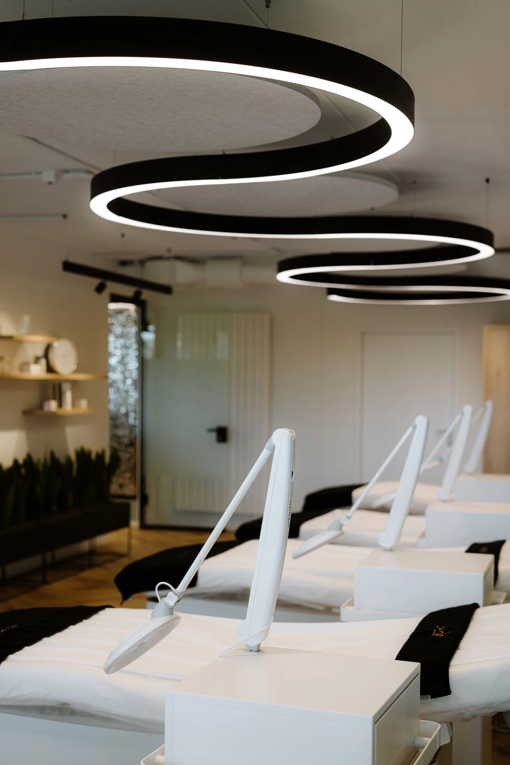 A curved, S-shaped SUPER-G pendant luminaire provides direct and indirect light and creates a relaxing atmosphere in a wellness and massage room.