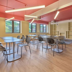 Square profile system with red end caps flexibly arranged on the ceiling – functional lighting for canteen and recreation area